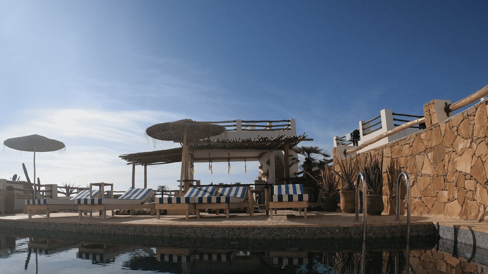 Le rooftop de Surf and Friends Lodge : la piscine, les transats à rayures et la terrasse ombragée face à l'Atlantique